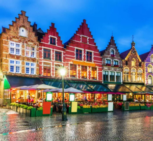 Bunte historische Giebelh&auml;user am Marktplatz in Br&uuml;gge bei Abendstimmung mit Stra&szlig;encaf&eacute;s und nassem Kopfsteinpflaster.