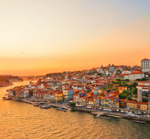 Abendstimmung über der Altstadt von Porto, Portugal, mit bunten Häusern am Flussufer und goldener Himmelsfärbung.