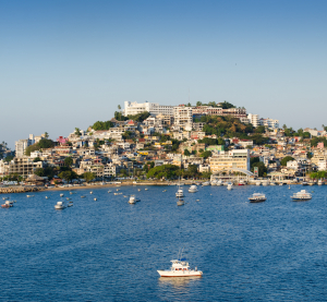 Blick auf Acapulco mit vielen Booten im Wasser und H&auml;usern am Hang.