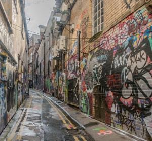 Schmale Gasse in Bristol, deren Wände vollständig mit bunten Graffiti und Street-Art bedeckt sind.