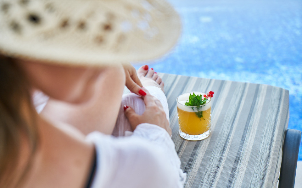 Frau am Hotelpool mit Cocktail