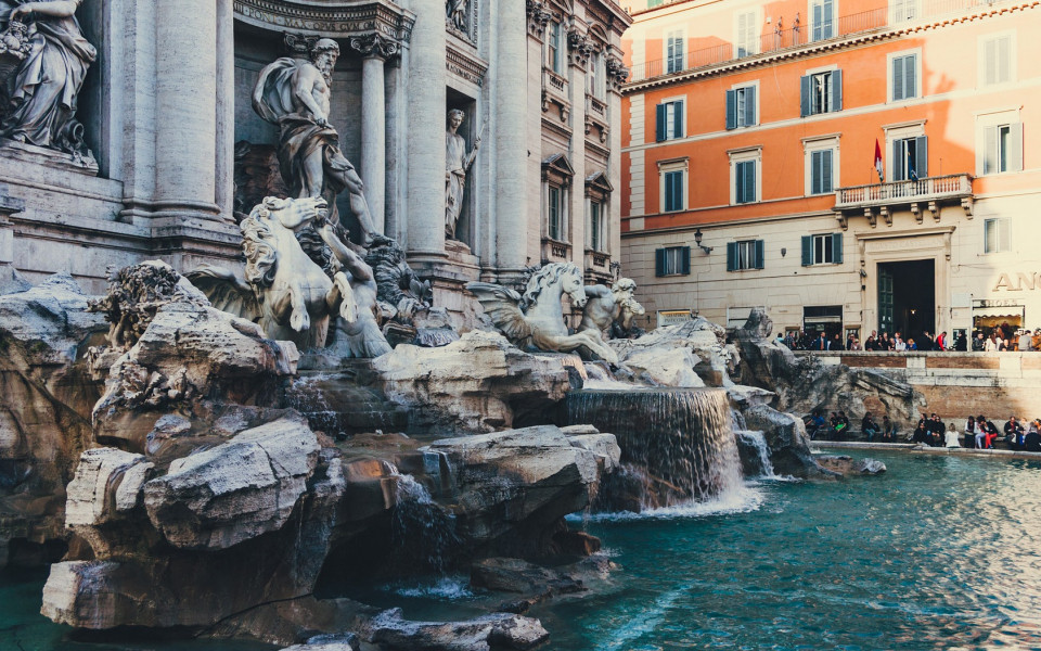Majestätischer Trevi-Brunnen mit kunstvollen Skulpturen und türkisblauem Wasser, umgeben von historischen Gebäuden.