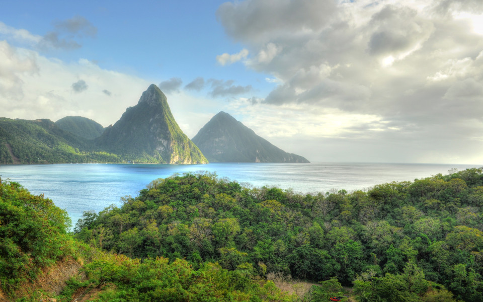 Zwei steil aufragende Vulkankegel der Pitons auf der Karibikinsel St. Lucia, umgeben von Meer und tropischem Wald.