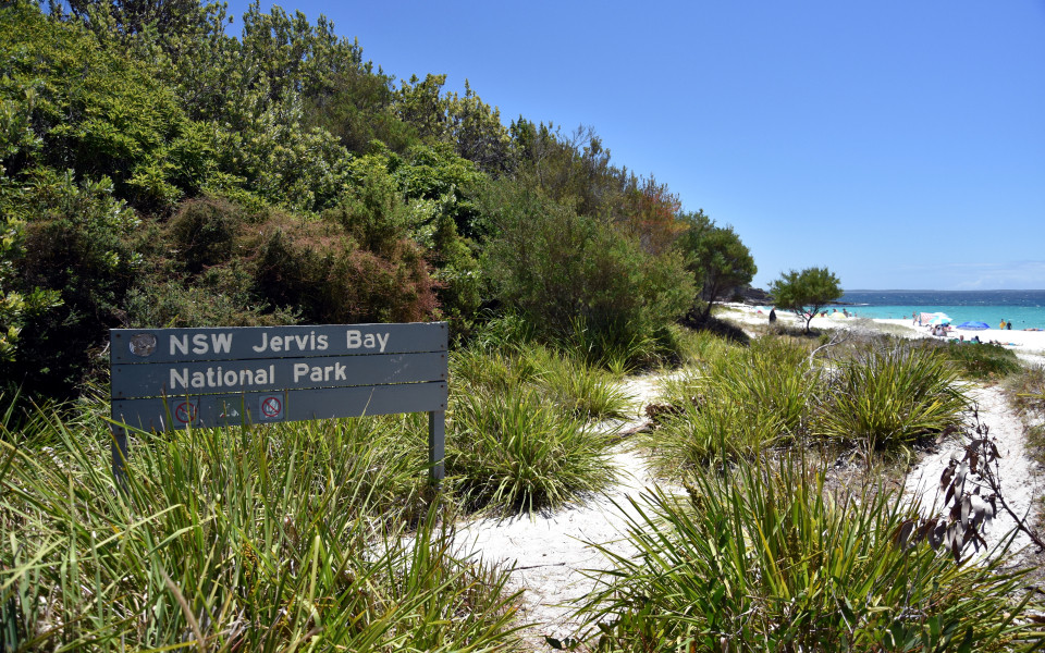Schilder des Jervis Bay Nationalparks, mit Blick auf den weißesten Sandstrand der Welt von Hyams Beach und das türkisfarbene Meer.