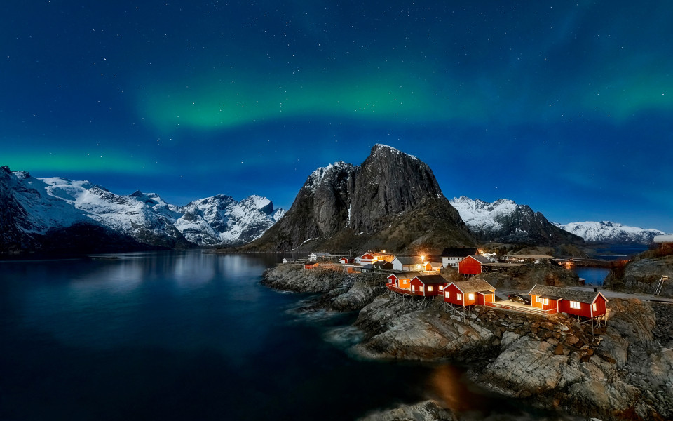 Fischerdorf auf den Lofoten, umgeben von schroffen Bergen und spiegelndem Wasser