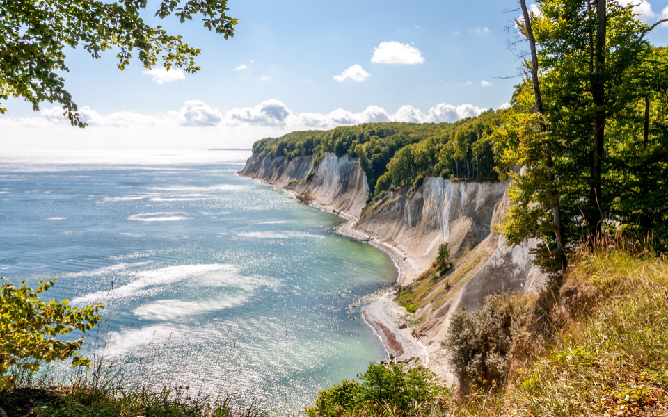 Die Kreidefelsen auf der Insel R&uuml;gen an der Ostsee, umgeben von gr&uuml;nen W&auml;ldern und dem klaren blauen Wasser.