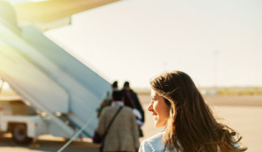 Junge Passagierin geht vom Flughafenterminal zum Abflugflugzeug.